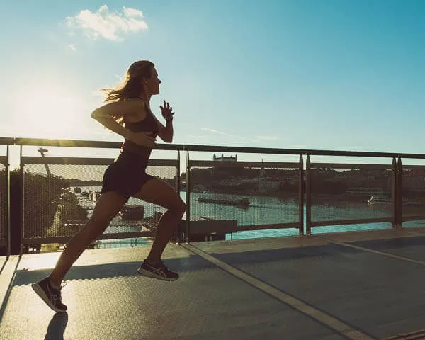 a woman running on a bridge over looking a body of water