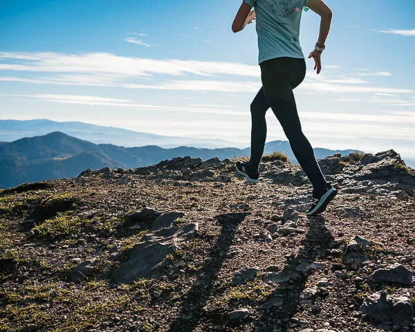  a woman running on top of a mountain